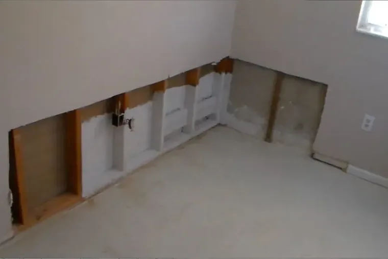 Drywall cut away near the floor so the cavity can dry