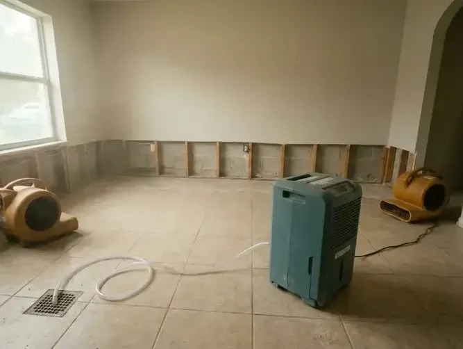 A dehumidifier and air movers drying a room after the baseboards came off