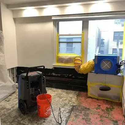 Dehumidifier and air movers drying a living room floor after a slab leak