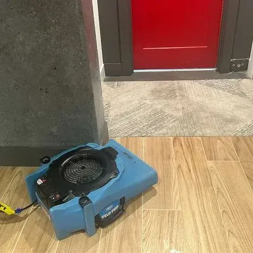 Air mover drying a wood-look tile floor near an open doorway, Bellflower water damage