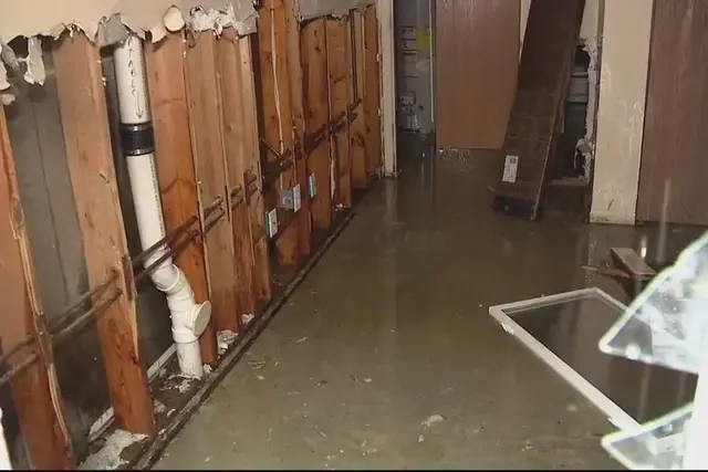 Standing water and opened wall cavities after a pipe burst inside a home