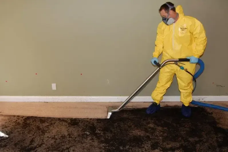 A technician in protective gear working on a sewage backup cleanup